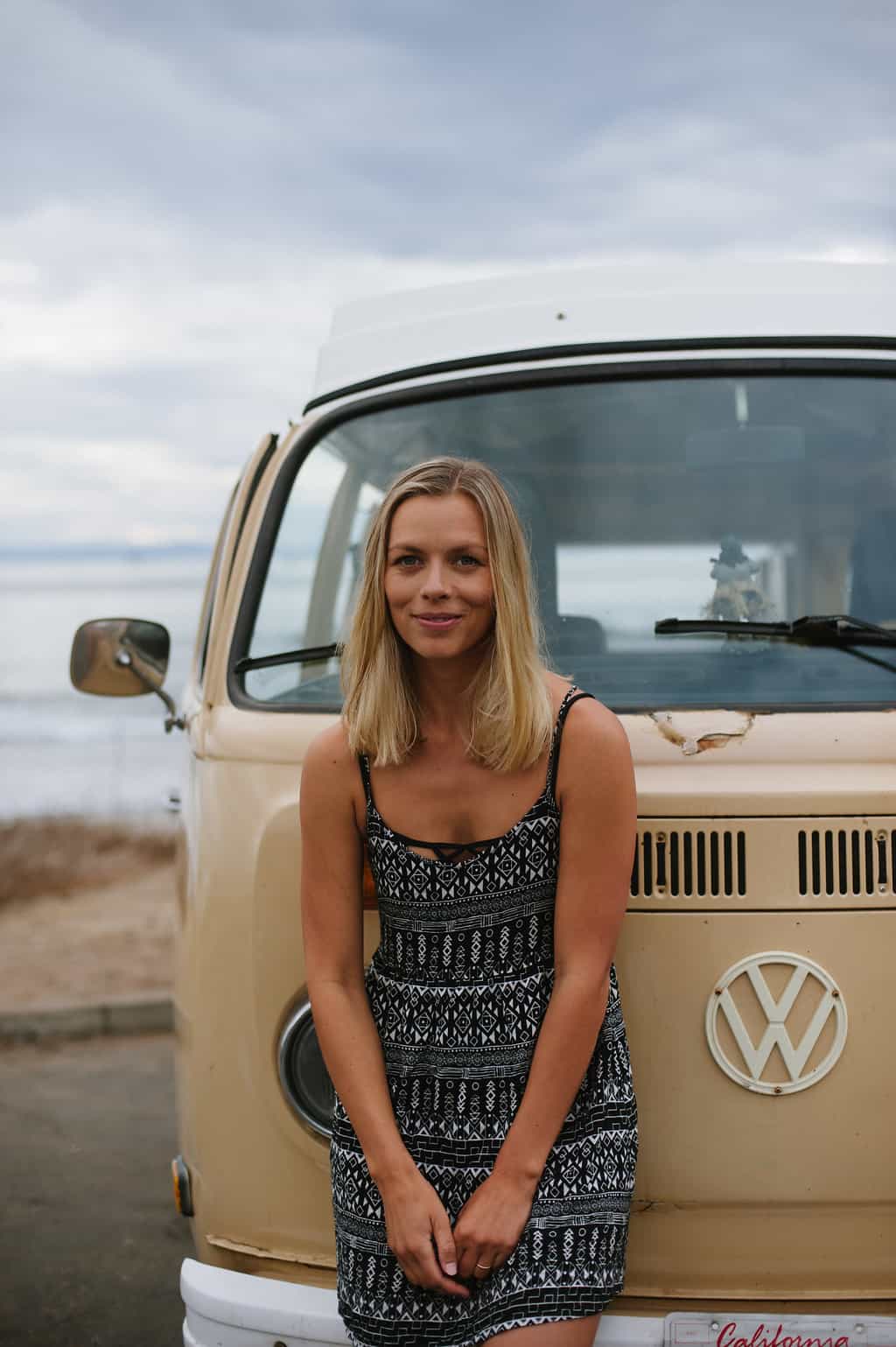 vw bus road trip woman leaning against front of van