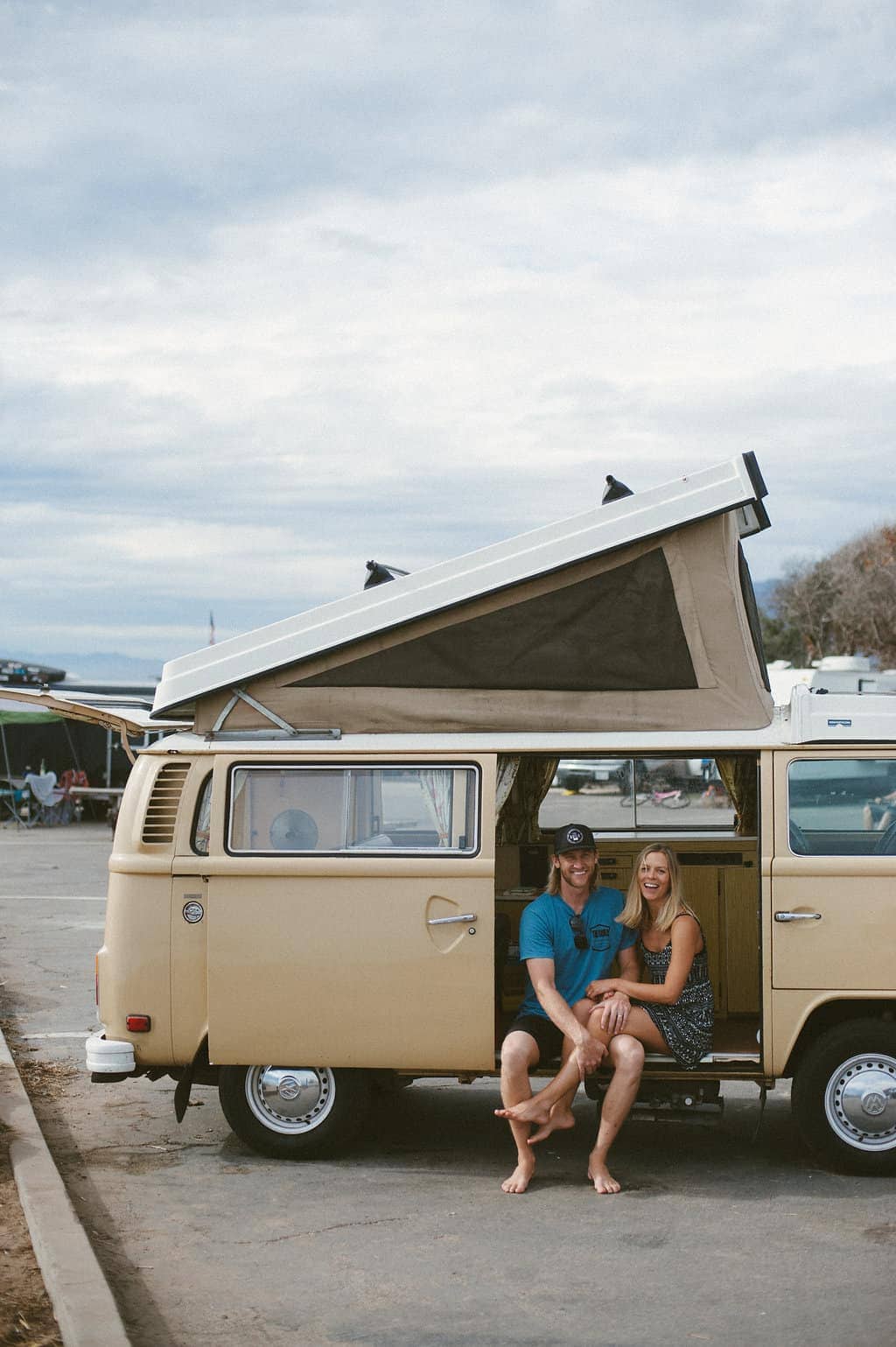 vw bus road trip couple sitting in slider door opening smiling