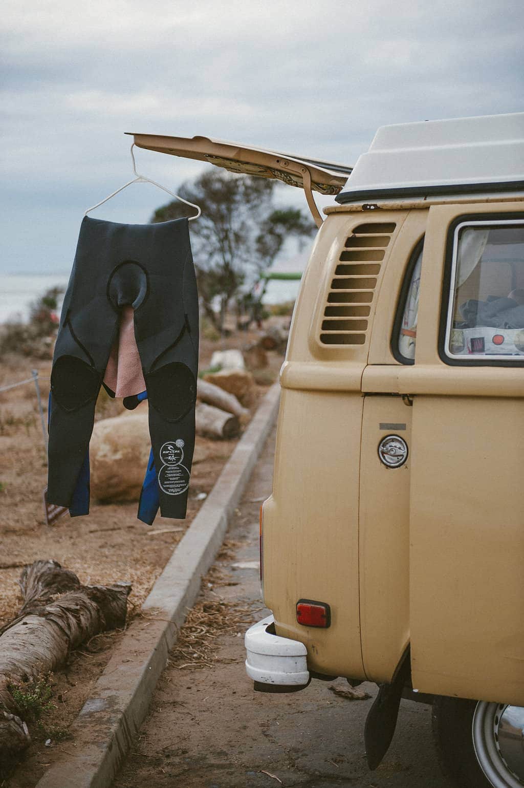 vw bus road trip wetsuit hanging from back of vw bus