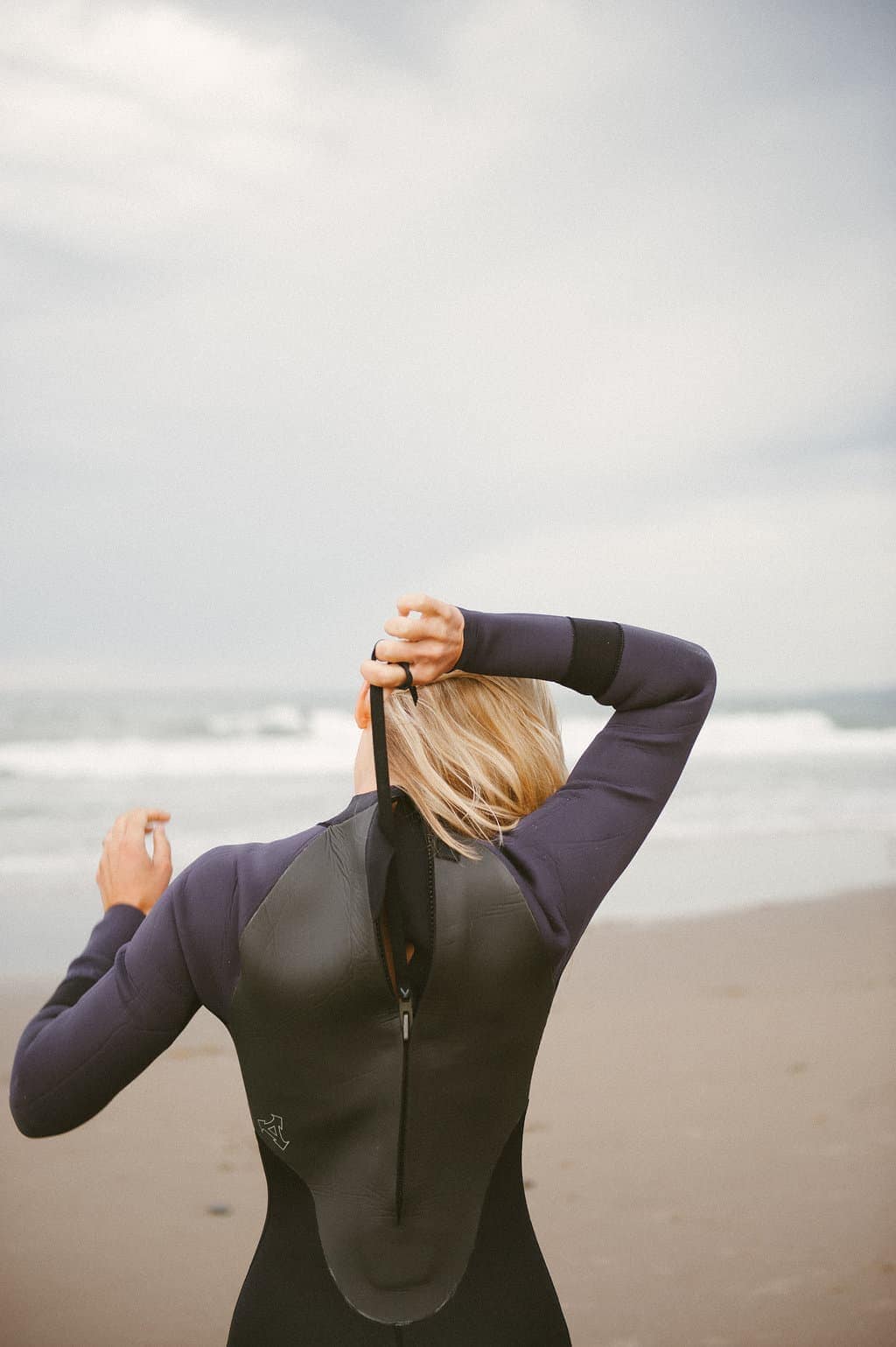 female surfer zipping up backzip wetsuit