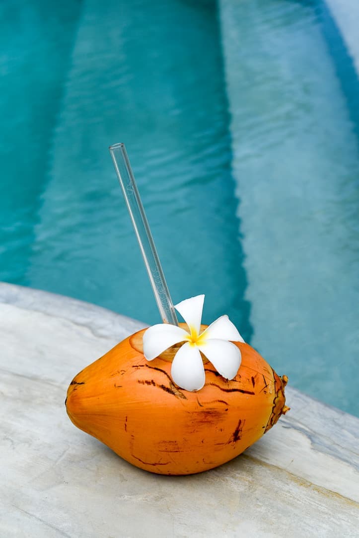 orange coconut with glass straw poolside