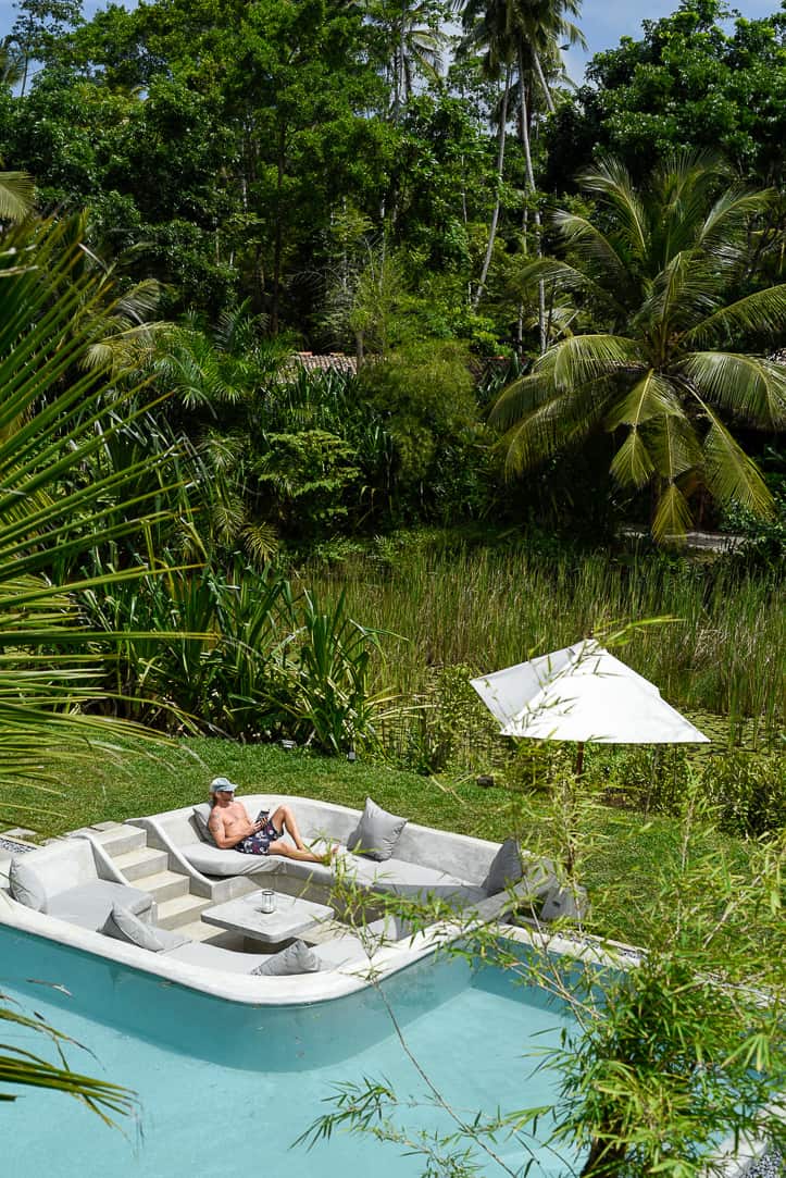 man lounging by pool in tropical paradise