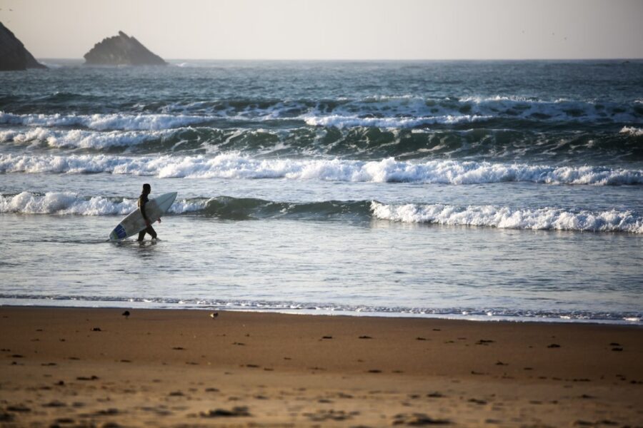 surfer walking into waves portugal