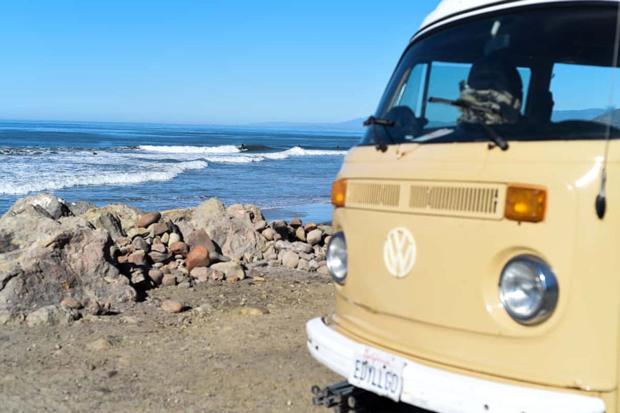 vw camper bus with surfer in background