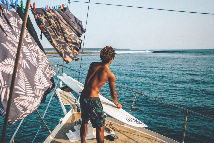 surfer on boat scouting waves wearing boardshorts by surf brand Roark Revival