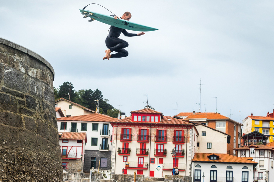 surfer jumping into ocean wearing patagonia wetsuit