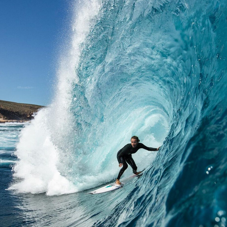 woman surfing large wave wearing a oneill wetsuit