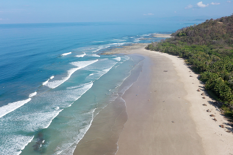 praia de areia larga com ondas pequenas para aprender a surfar