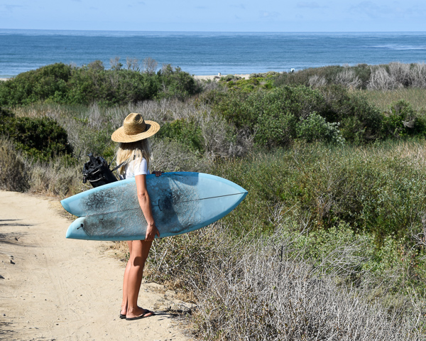 female surfer holding fish shortboard overlooking trestles