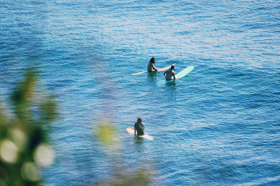 três surfistas iniciantes sentados no oceano esperando por ondas