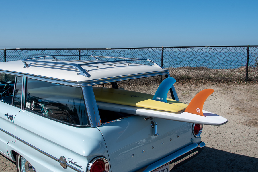 Carro antigo com duas pranchas de surfe no oceano