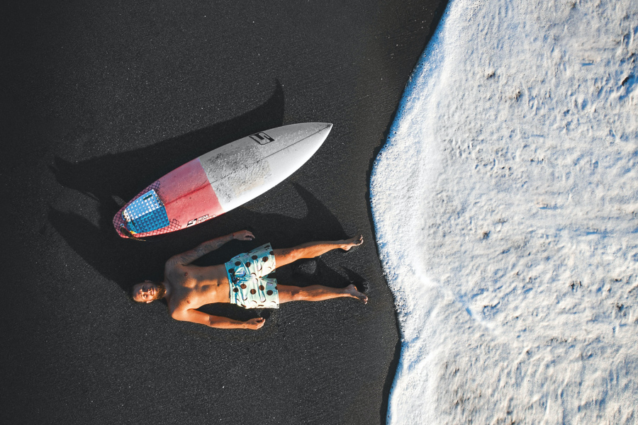 Man lying on sand next to surfboard - How to choose a surfboard depends on your weight and fitness