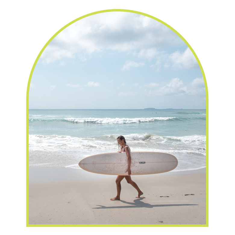female surfer carrying surfboard at beach