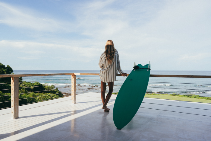 garota com prancha de surfe na varanda com vista para o mar