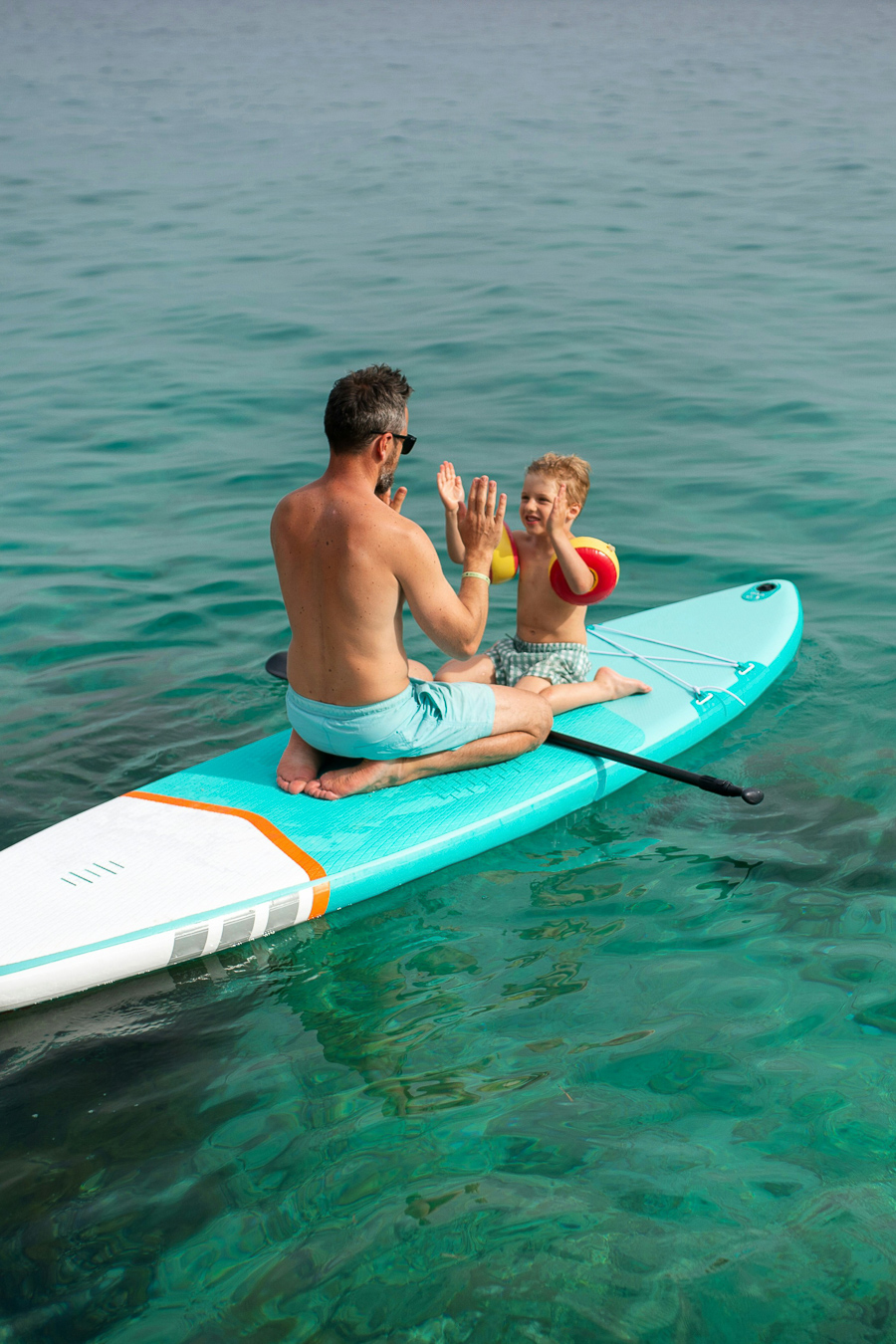 father and toddler son floating on SUP